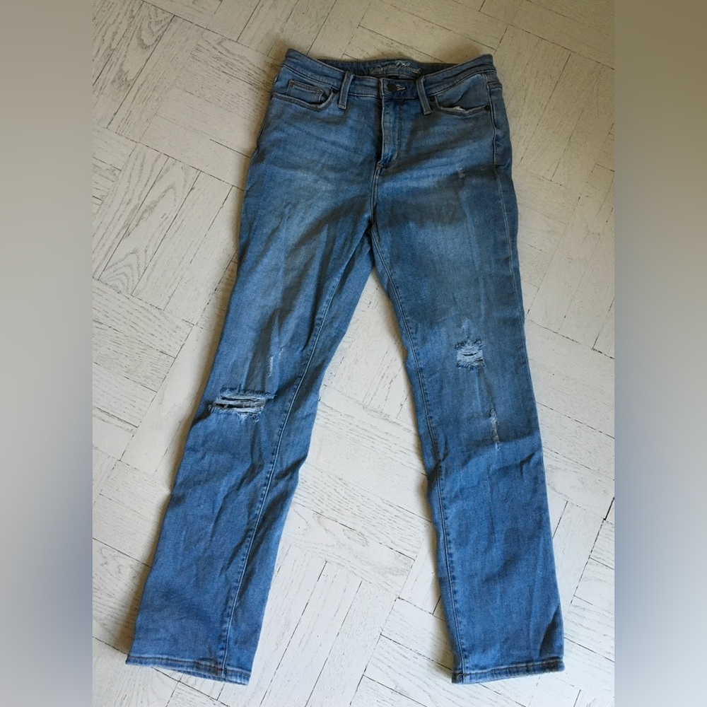 Faded jeans with intentional tears.